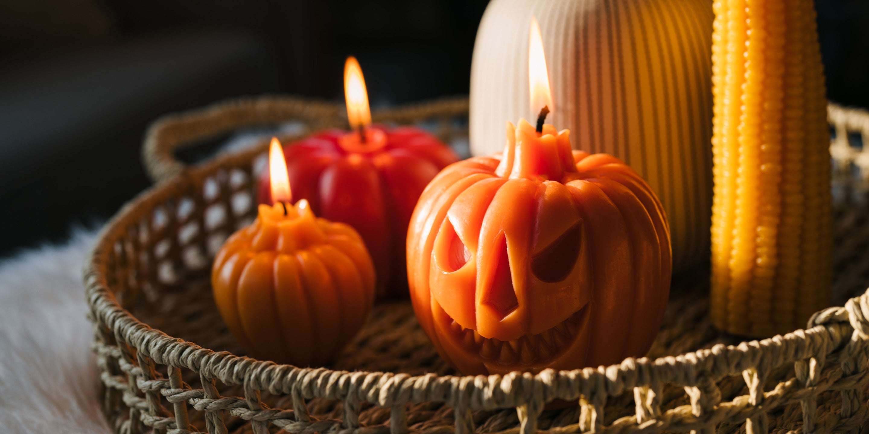 Sunbeam Candles assorted pumpkin, jack-o-lantern and corn cob candles lit in a wicker basket