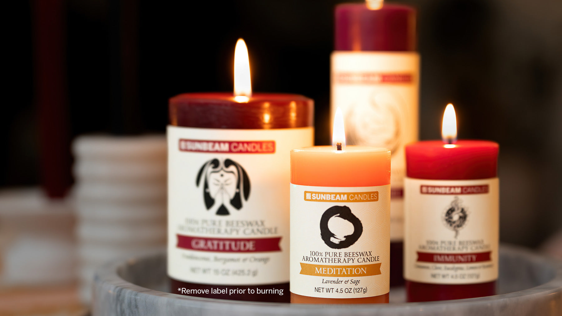 Sunbeam Candles pure beeswax aromatherapy pillars lit on a tray with a blurred background