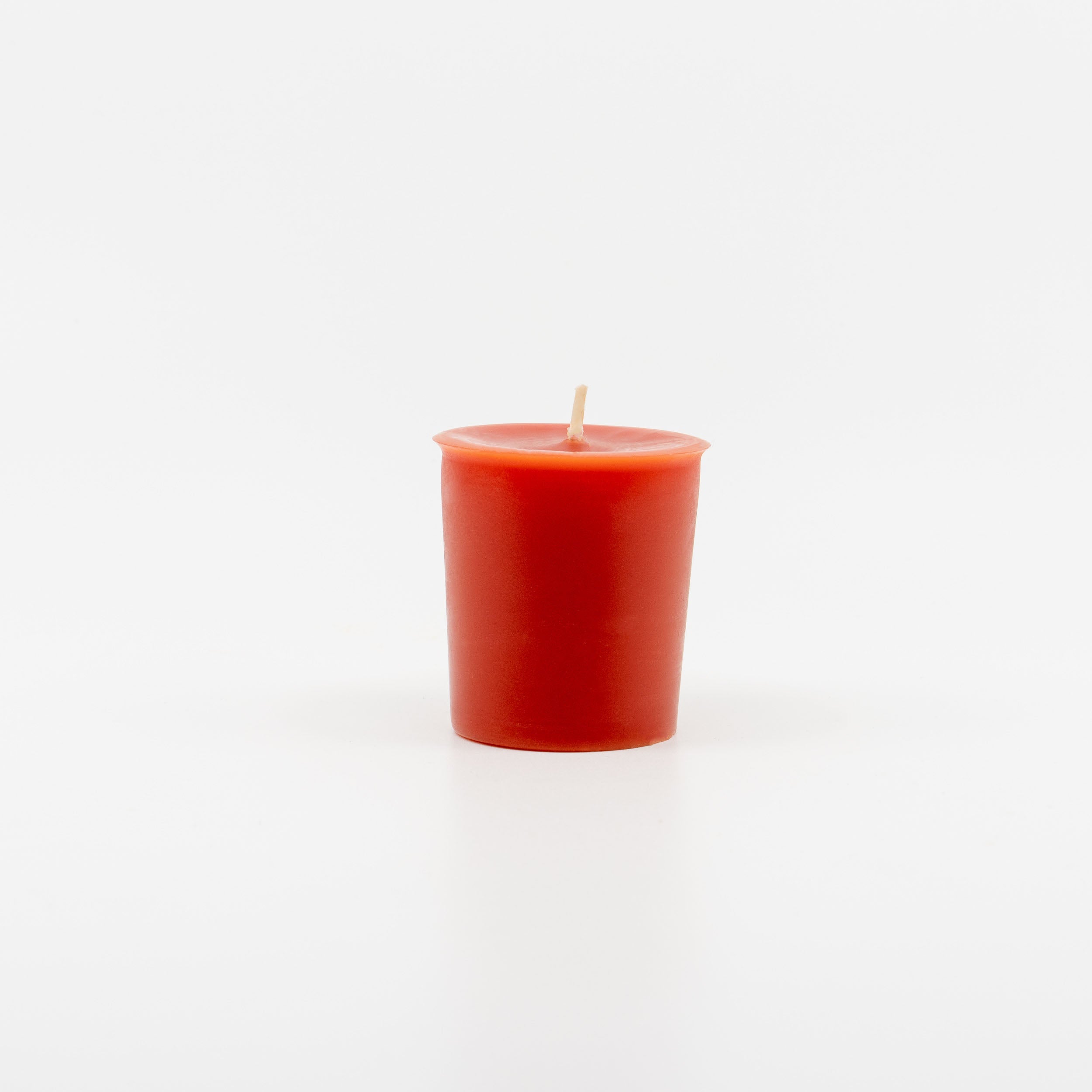Sunbeam Candles Pure Beeswax reddish-orange Orange, Grapefruit & Cedarwood votive candle with white background