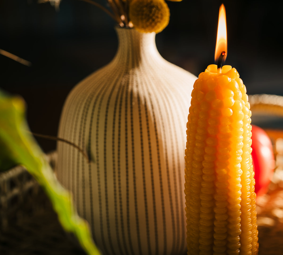 Corncob candle lit on tray with vase
