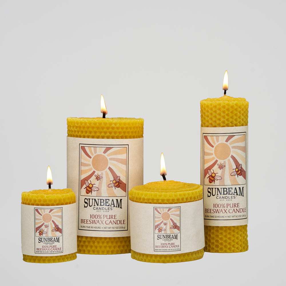 Four lit Sunbeam Candles Beeswax Honeycomb Pillars with a white background.