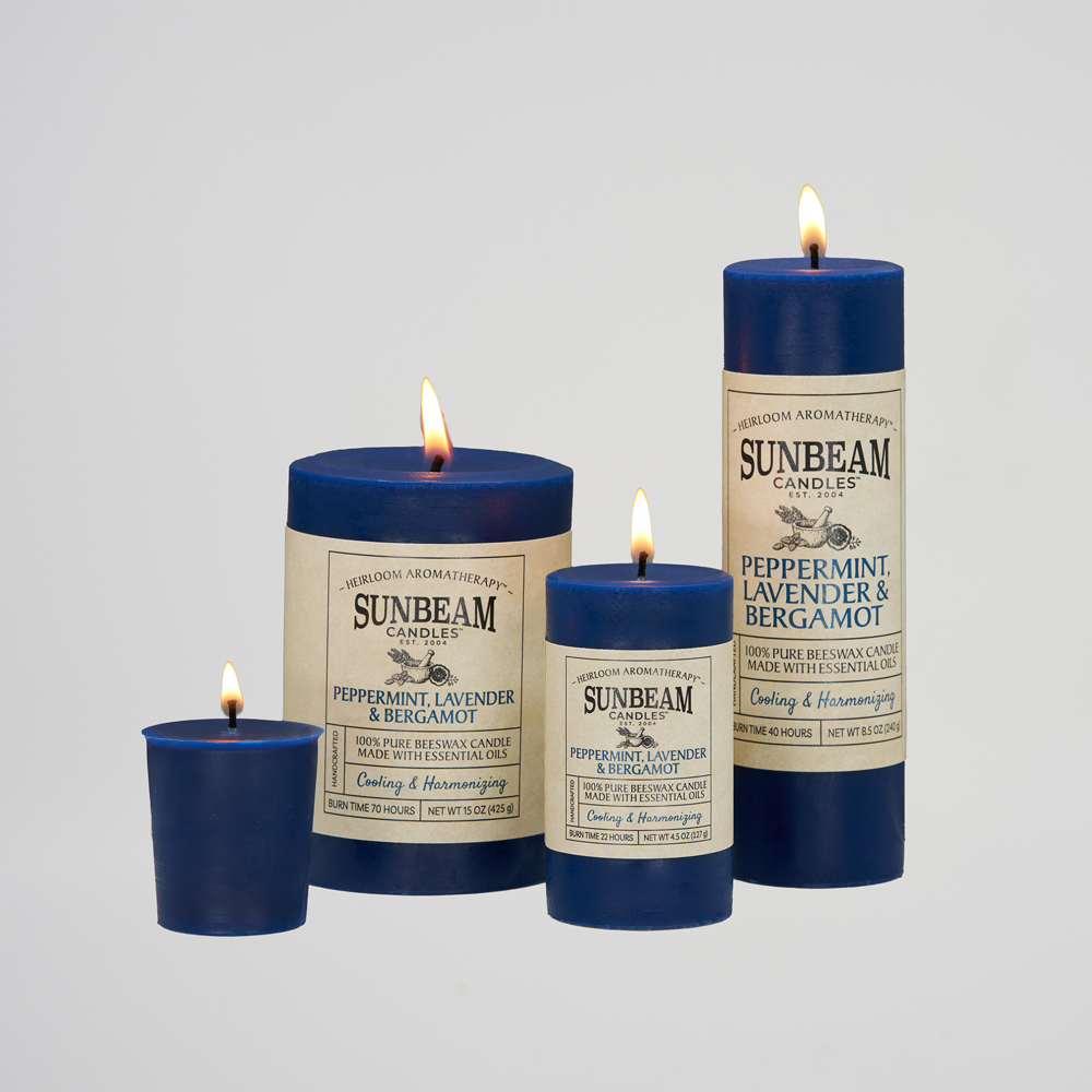 Sunbeam Candles lit blue Peppermint, Lavender & Bergamot pillar candles on a white background