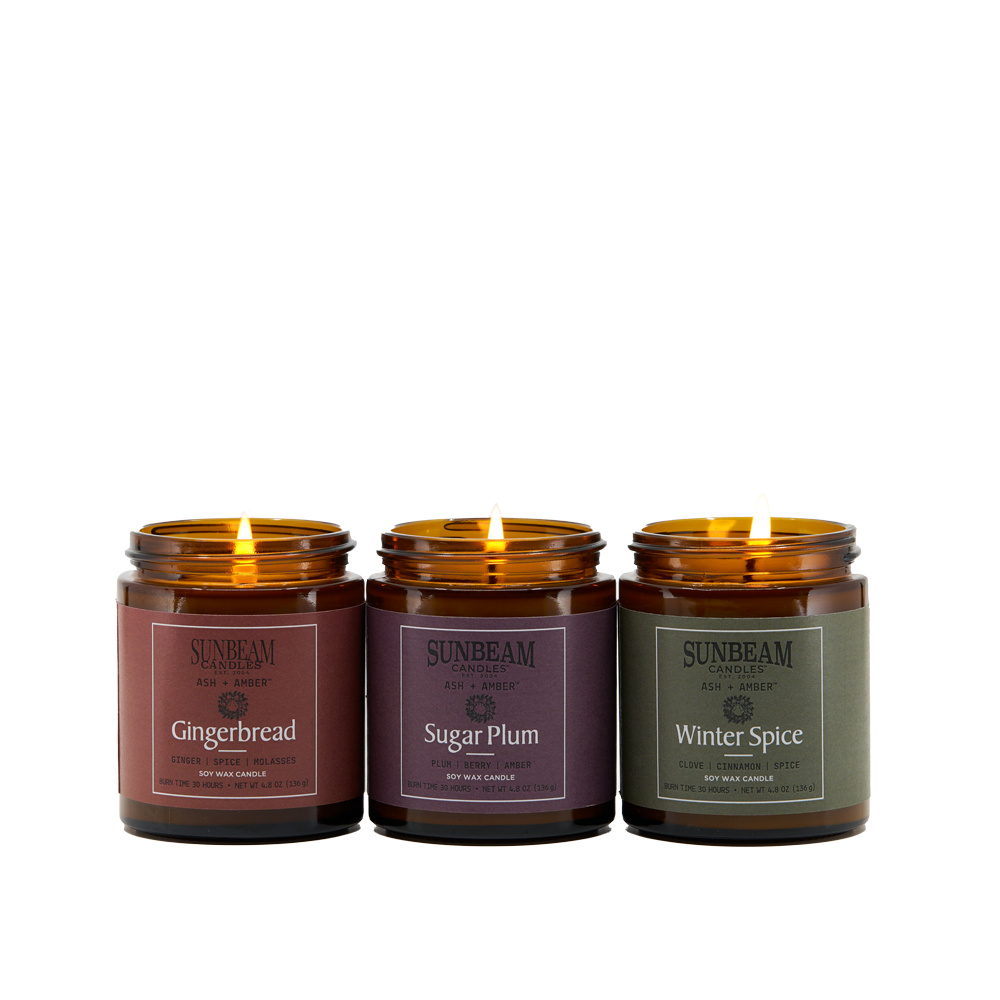 Sunbeam Candles lit Ash + Amber Winter Scent Soy Wax jar candles on a white background