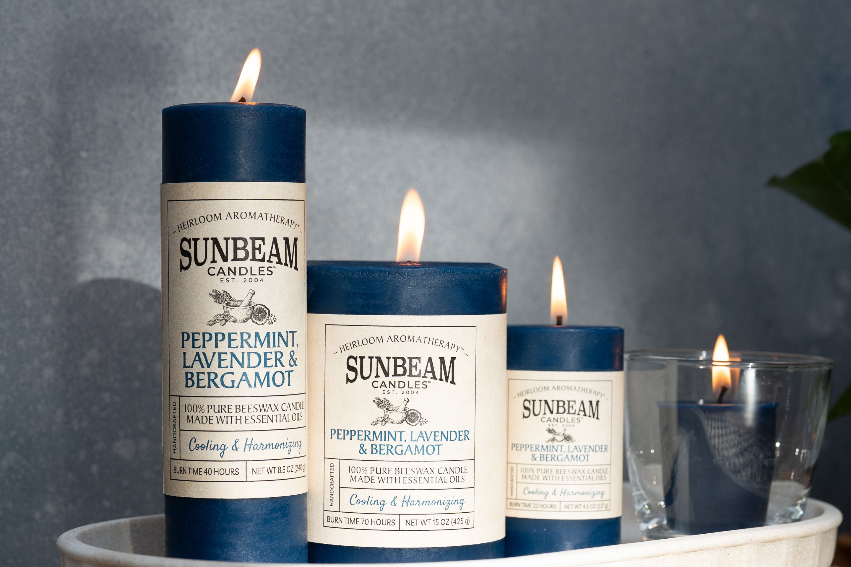 Sunbeam Candles Pure Beeswax lit Blue Peppermint, Bergamot & Lavender Pillar & Votive Candles in a dish with a grey background