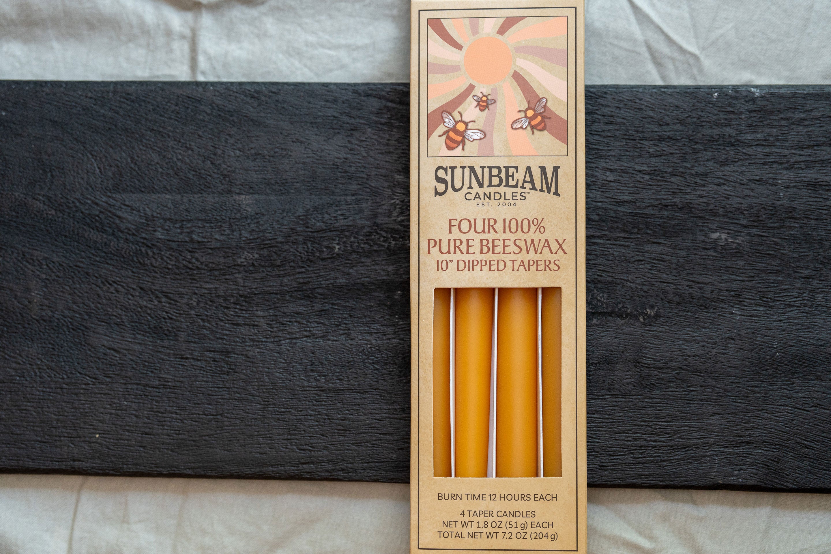 2-pair box of Sunbeam Candles 10" Dipped Beeswax Natural Gold Tapers on a wooden surface