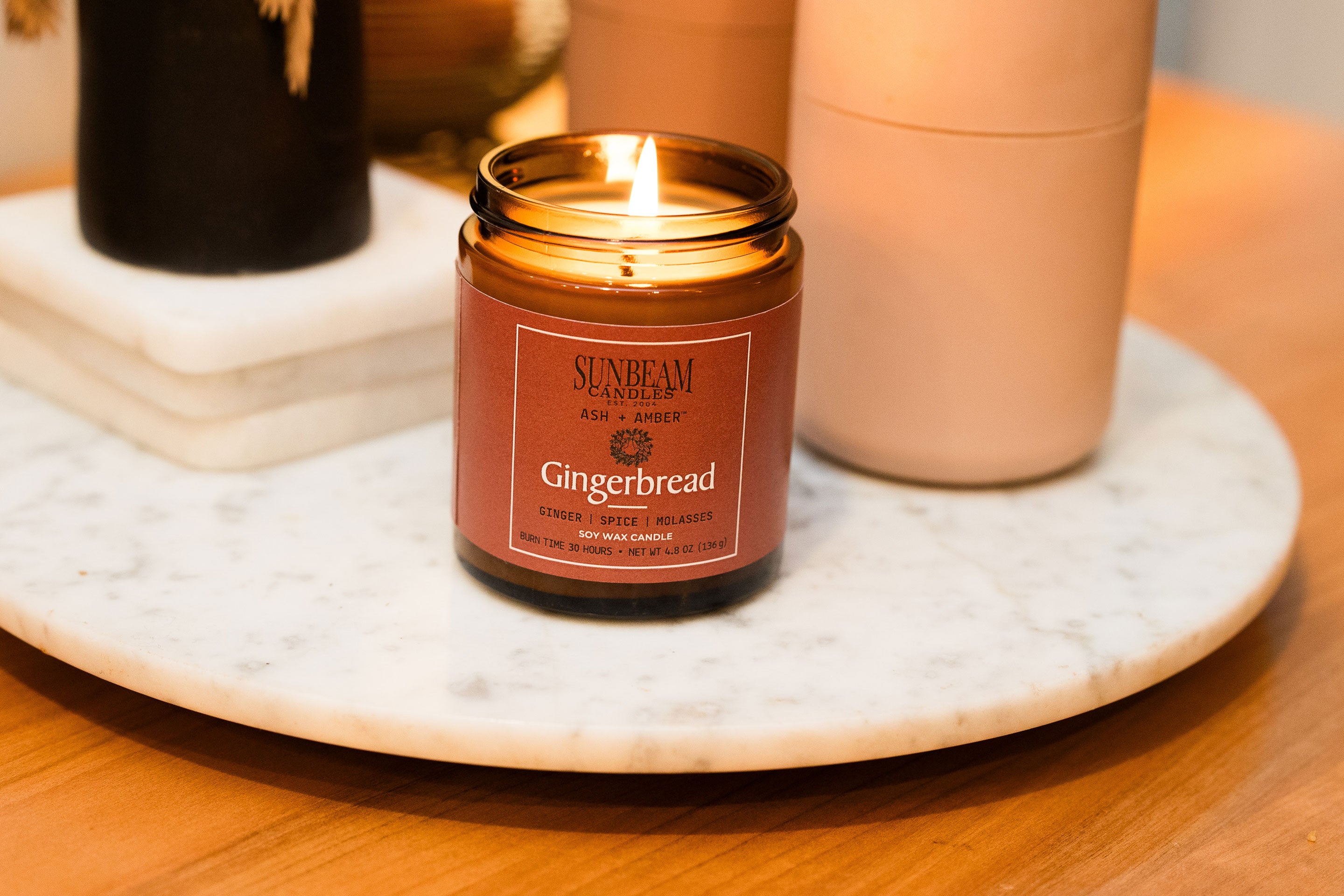 Sunbeam Candles Ash + Amber Fall Scent Gingerbread lit soy wax jar candle on a marble tray