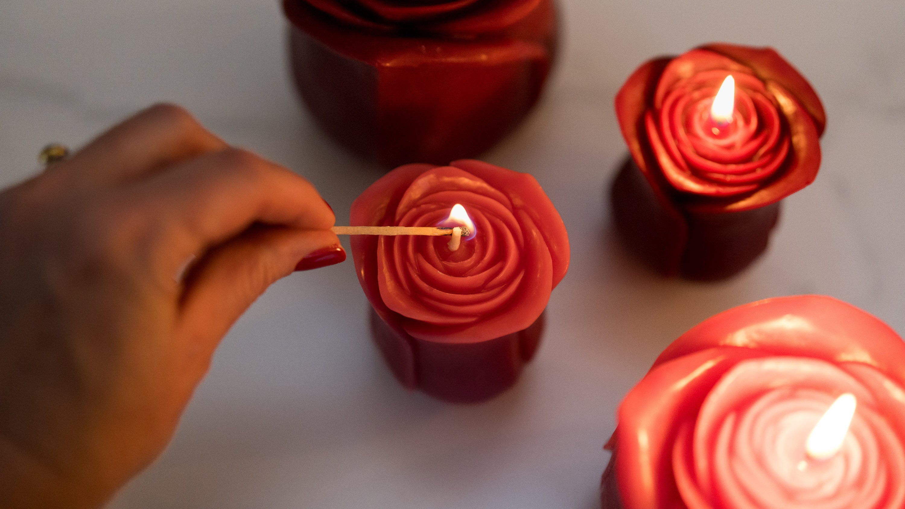Sunbeam Candles pure beeswax rose candles on a table being lit by a hand
