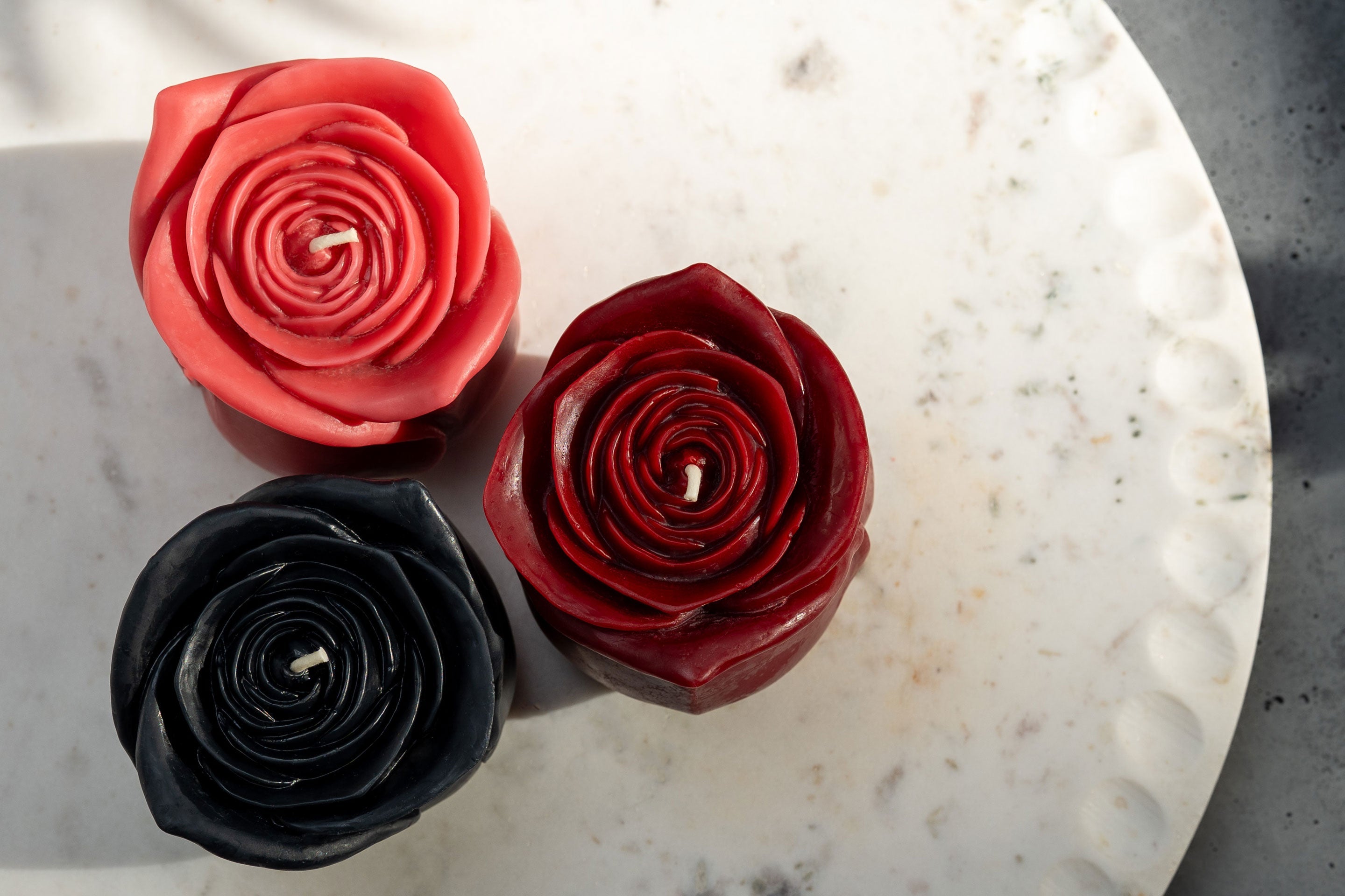 Sunbeam Candles red, black & pink Grande Rose candles on a white plate