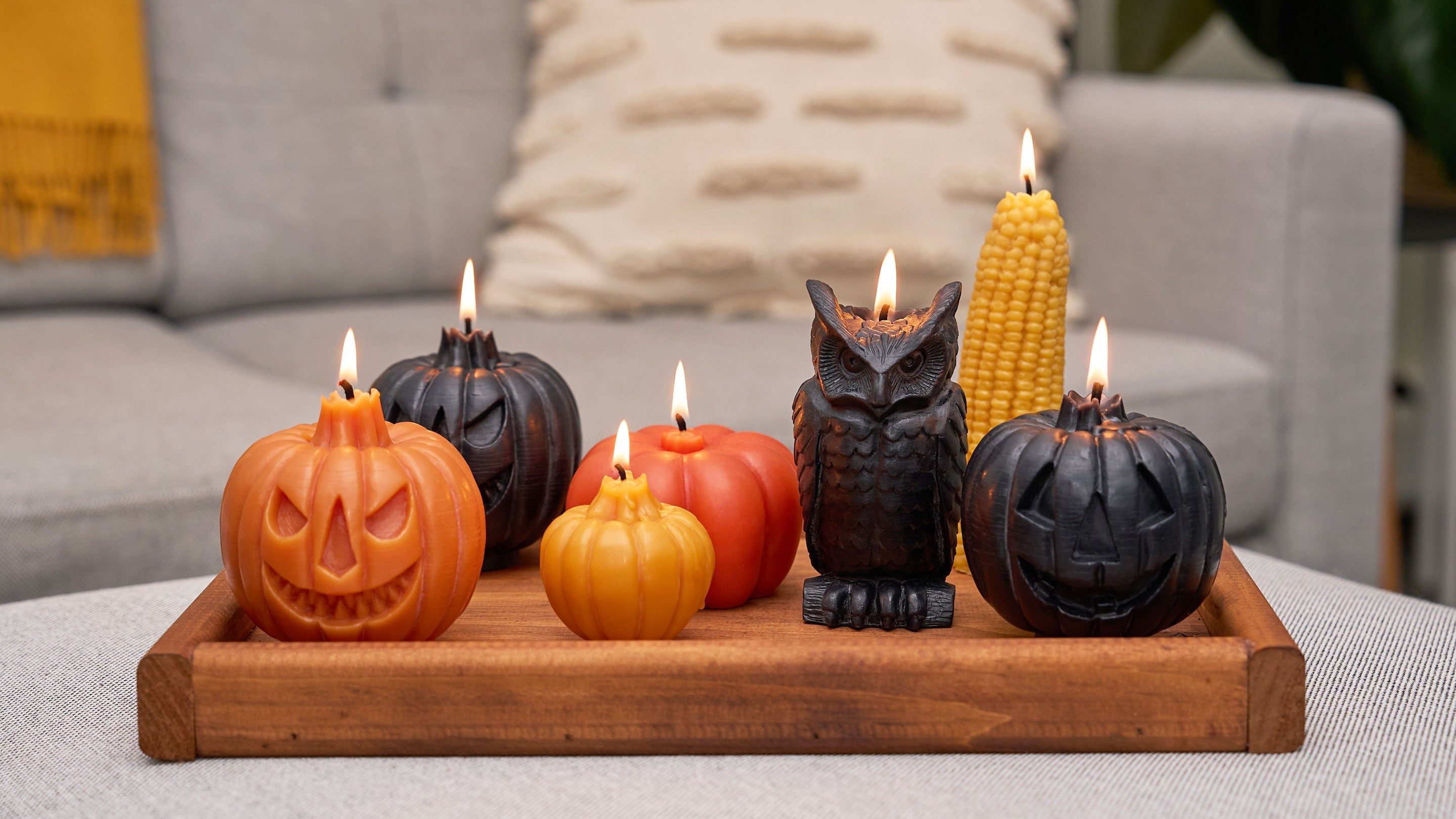 Sunbeam Candles assorted pure beeswax Harvest themed Specialty Shape candles on a wood tray with a couch behind them