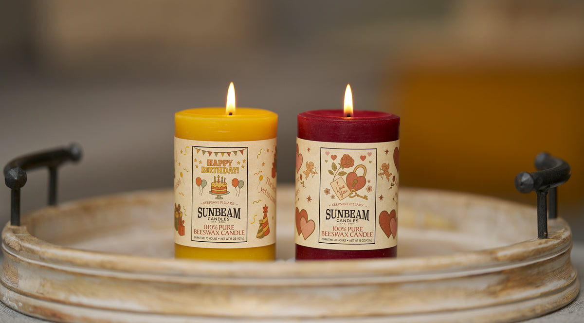 Sunbeam Candles pure beeswax pillars being lit by a hand on a wood surface with a plant behind it