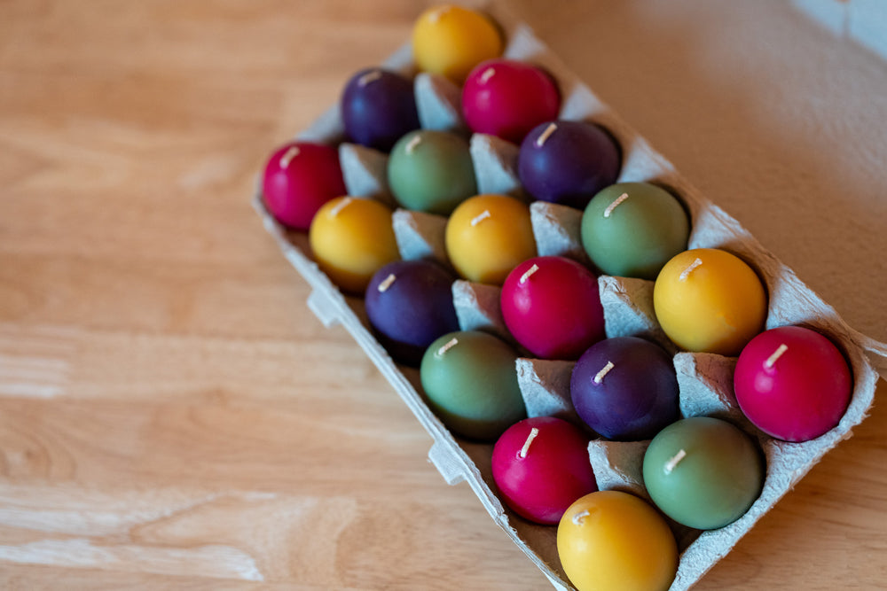 Colorful candles in an egg carton on a wooden surface