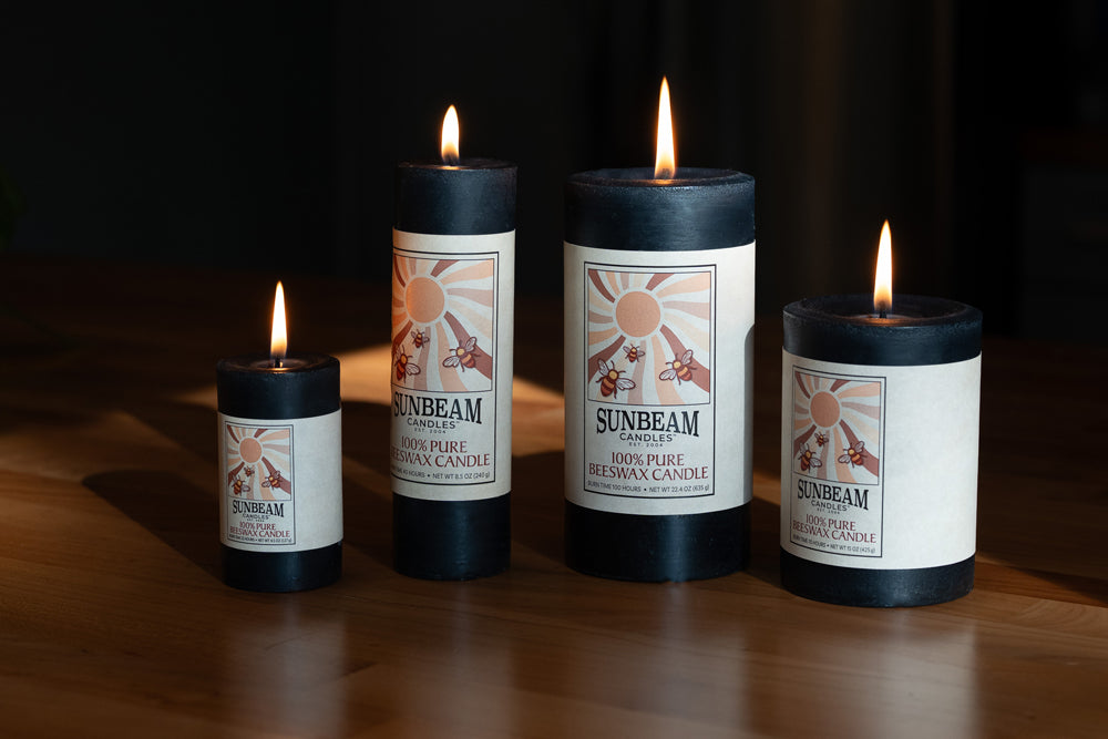 Four Sunbeam candles on a wooden surface with a dark background
