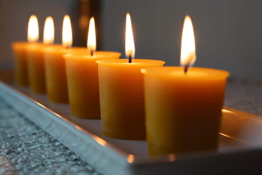a line of lit yellow votive candles on a tray