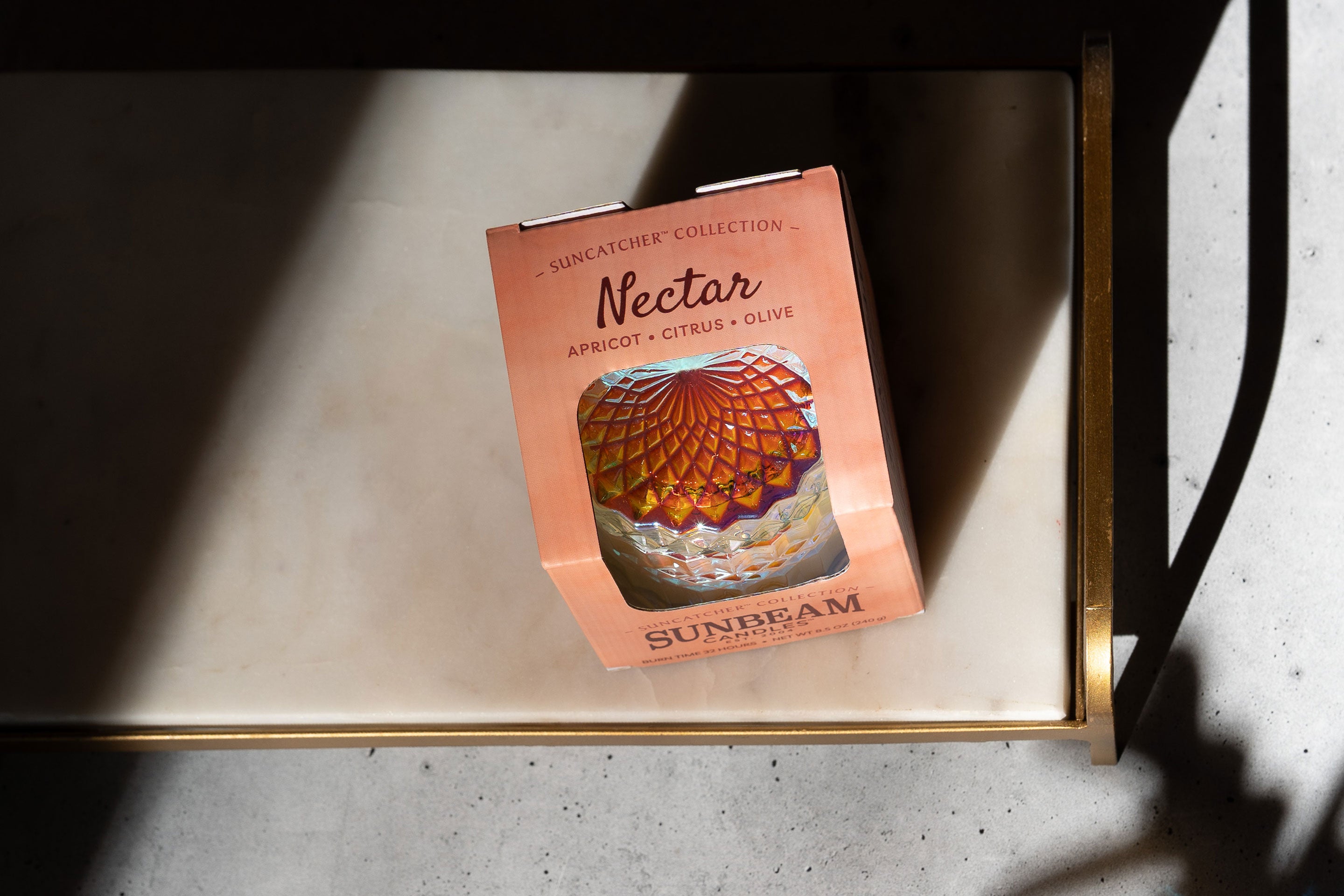 Sunbeam Candles SunCatcher Nectar scent apricot, coconut & soy wax iridescent container candle in box on white tray with shadows