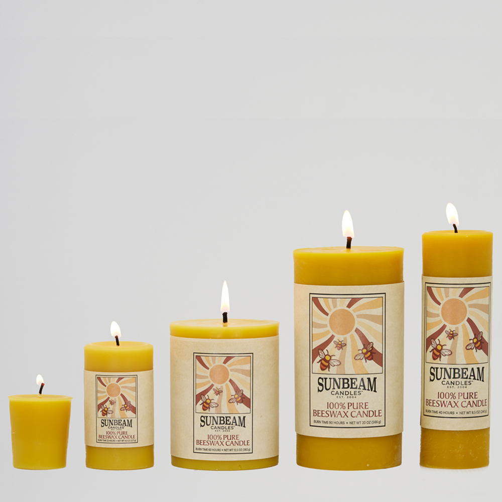 Sunbeam Candles Smooth Beeswax Pillars in four sizes and a votive lit with a white background.