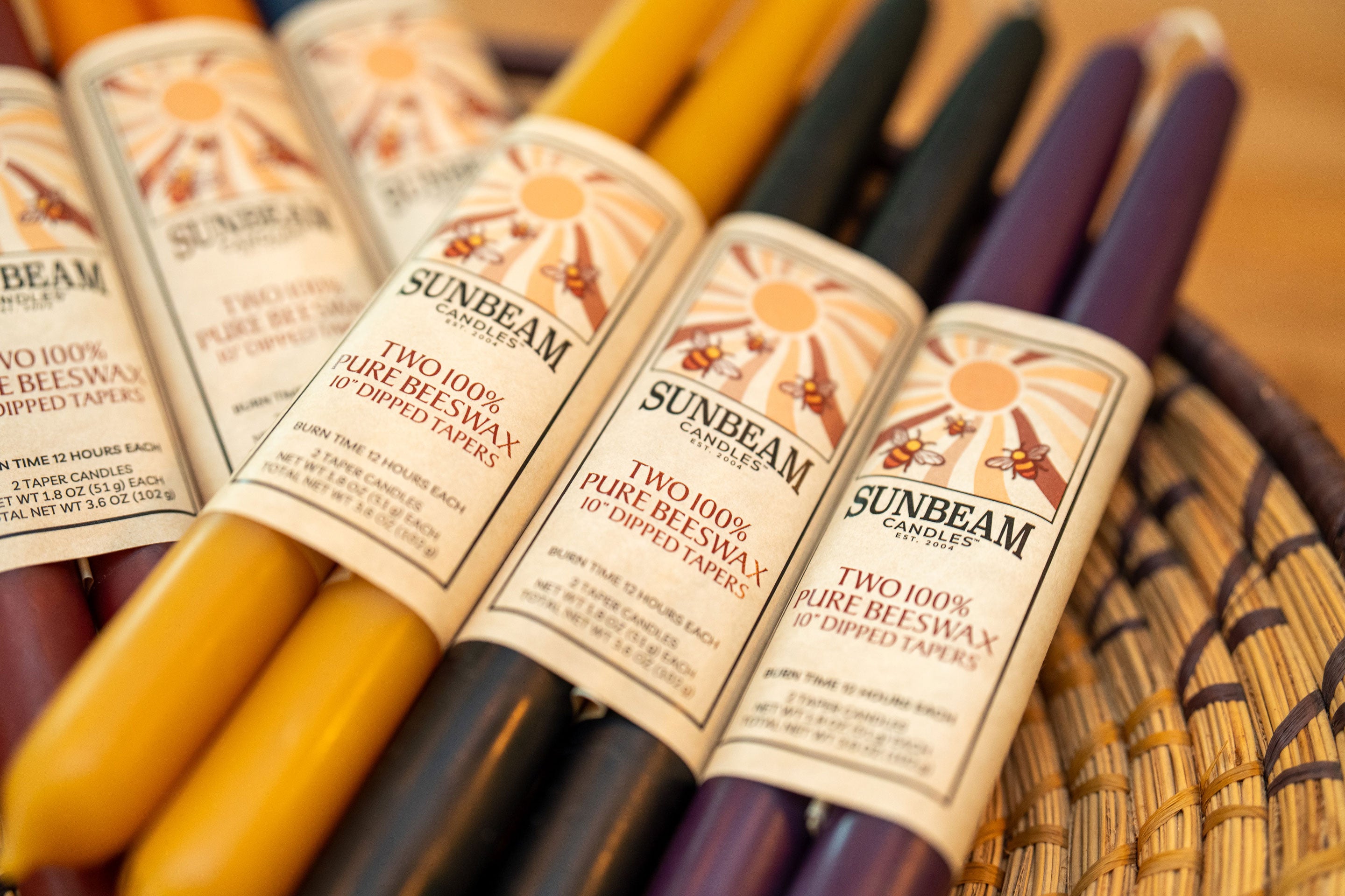 Sunbeam Candles 10" dipped beeswax wrappe tapers in various colors in a basket- Apicot, Crimson, Indigo, Midnight Black, Natural Gold & Plum
