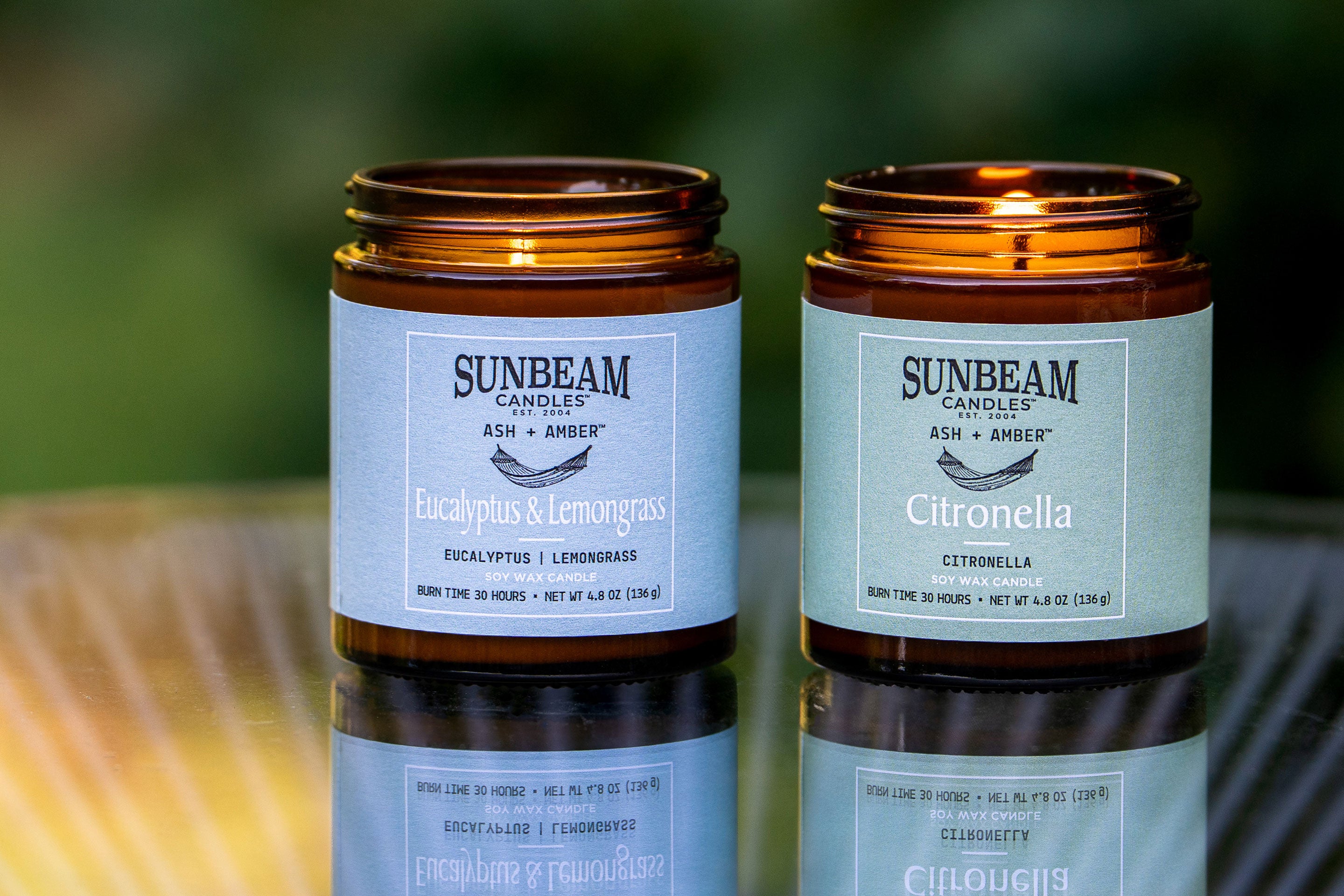 Sunbeam Candles Ash + Amber Summer Scent soy wax jar candles on a table with a blurred background