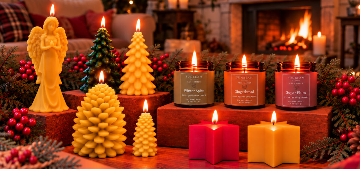 Assorted lit winter holiday themed candles on a table with festive decorations and a couch and fireplace in the background